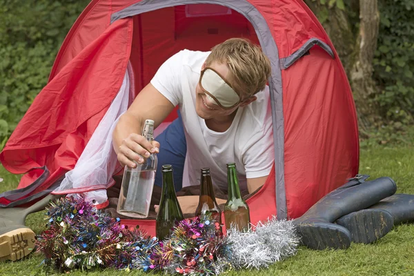 A young camper with eye shade reaches out from a tent for a water bottle — Stock Photo, Image