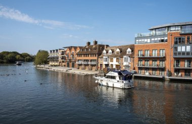 Eton, Buckinghamshire, İngiltere, İngiltere. 2020 yılı. Thames nehri boyunca modern konutlardan geçen kabin kruvazörü Windsor, Eton köprüsünden Eton nehir kenarına bakıyor.. 
