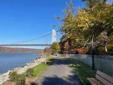 Manhattan, New York, ABD. 2020 yılı. Hudson Nehri boyunca sonbahar renklerinde ağaçlar George Washington Köprüsü 'ne yaklaşıyor..