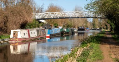 Kennet ve Avon Canal, Aldermaston Wharf, Berkshire, İngiltere, İngiltere. 2021 yılı. Berkshire kırsalındaki Kennet Nehri 'ndeki yaya köprüsünün altında Kennet ve Avon kanallarını yüzen yüzen yüzen yüzen evler..