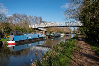 Kennet ve Avon Canal, Aldermaston Wharf, Berkshire, İngiltere, İngiltere. 2021 yılı. Berkshire kırsalındaki Kennet Nehri 'ndeki yaya köprüsünün altında Kennet ve Avon kanallarını yüzen yüzen yüzen yüzen evler..