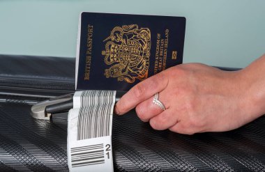İngiltere. 2021 yılı. Yeni koyu mavi İngiliz pasaportu tatil bavuluyla gezginlerin elinde..