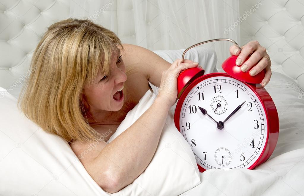 Woman with an alarm clock at wake up time