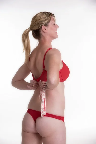 Woman wearing red underwear holding a tape measure — Stock Photo, Image