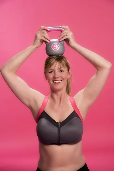 stock image Woman with a kettle bell on her head during a training session