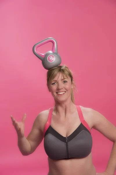 Woman with a kettle bell about to fall off her head — Stock Photo, Image