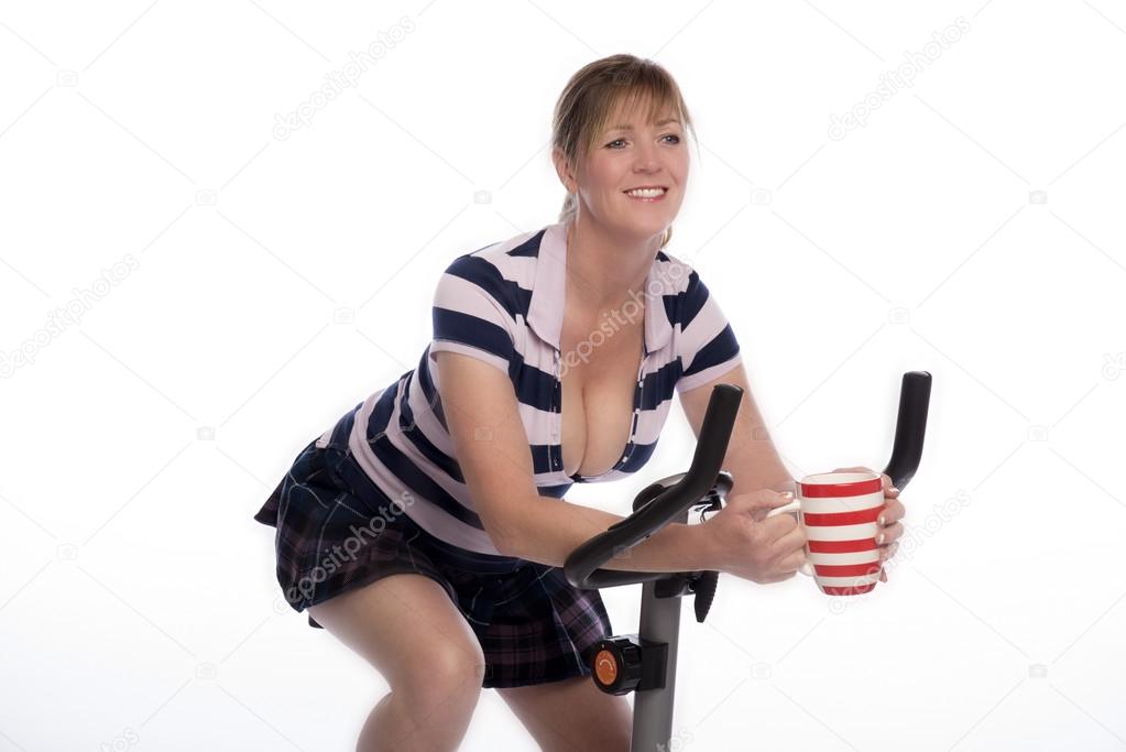 Woman on exercise bike with a mug of tea