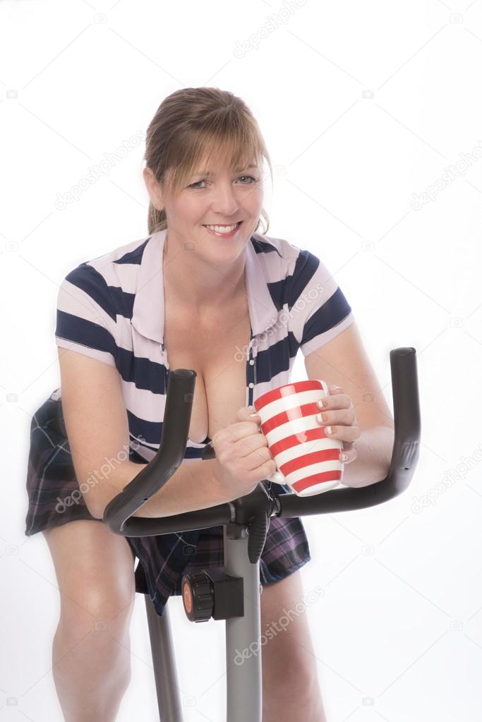 Woman on exercise bike with a mug of tea