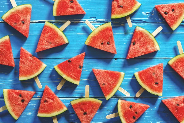 Wassermelone Scheibe Eis am Stiel auf blauem rustikalem Holz Hintergrund, Pop Stockfoto