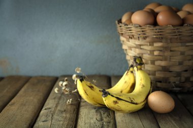 Muz ve ahşap masa üzerinde yumurta ile natürmort