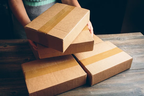 Girl's hands holding the package on the table. — Stock Photo, Image