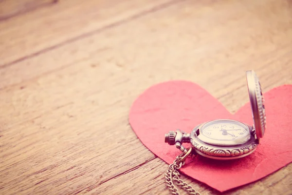 Collana lunga orologio da tasca in stile antico con un cuore di carta gelso rosso su una superficie di legno . — Foto Stock