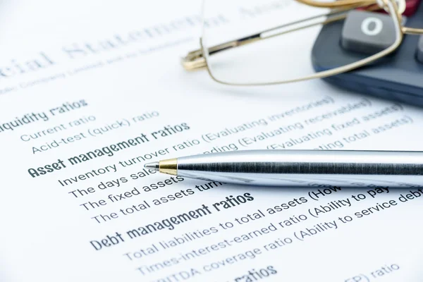 Caneta esferográfica azul, óculos de olho e uma calculadora em um papel de listas de verificação de análise financeira . — Fotografia de Stock