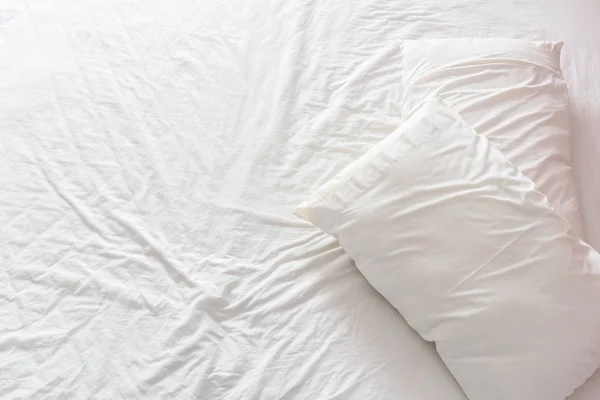 Vista superior de una cama desordenada / deshecha con sábana blanca arrugada y dos almohadas desordenadas en una habitación de hotel . —  Fotos de Stock