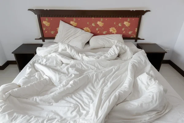 Onopgeruimd/ongemaakt bed met twee rommelige kussens en een witte verfrommeld deken in een hotel single (standaard) kamer. — Stockfoto