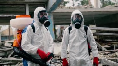 İşçiler terk edilmiş bölgedeki harabe binanın yanında duruyorlar