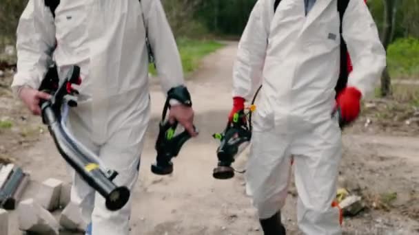 Takım elbiseli dezenfekte ekibi ellerinde solunum cihazlarıyla yürüyor. — Stok video