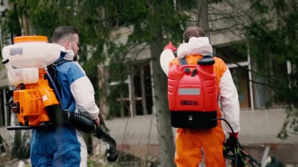 I lavoratori di disinfezione discutono l'aspersione a edificio rovinato — Video Stock