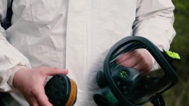 Dezenfeksiyon servisi çalışanı solunum cihazına filtre takıyor