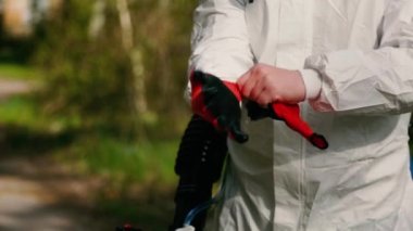 Dezenfekte servisi görevlisi ormanda kırmızı eldiven takıyor.