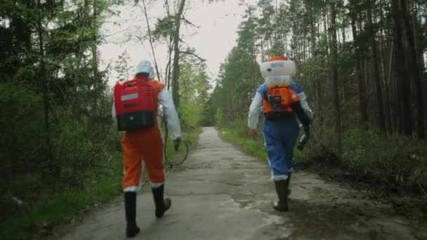 Мужчины эпидемиологи ходить по дороге и спрей тик репеллент — стоковое видео