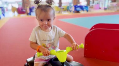 Küçük bir kız çocuk bisikleti sürüyor. Kapalı alanda denge bisikleti, aktif oyun ve motor becerileri geliştirmek için modern oyuncak.