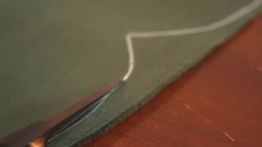 İşçi asker ya da işçi üniforması için kalın kumaş parçaları kesiyor. Taktik giysiler için kumaş kesme işlemi