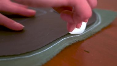 Kesmeden önce kumaşı tebeşirle işaretleyen bir terzinin yakın çekimi. Dikiş işlemi, el yapımı kıyafet üretimi