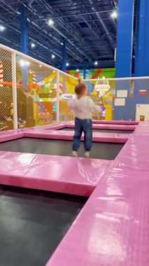İçerideki lunaparkta trambolinde zıplayan tatlı bir kız. Güvenli eğlence aktivitesi, enerjik çocukluk oyun alanı aileler için.