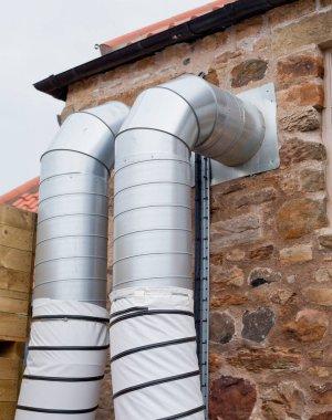 Eski Dtyle taş binasından dışarı sarkan kalın gümüş boruları olan havalandırma sistemi..