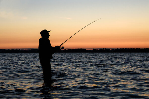 Силуэт рыбака на закате 