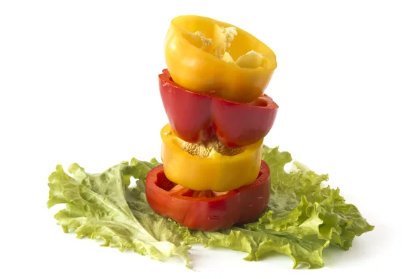 Geschnittene süße gelbe und rote Paprika auf Salatblättern lizenzfreie Stockfotos