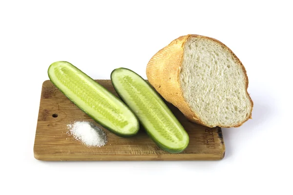 Gesneden komkommer en brood op een snijplank geïsoleerd op wit — Stockfoto