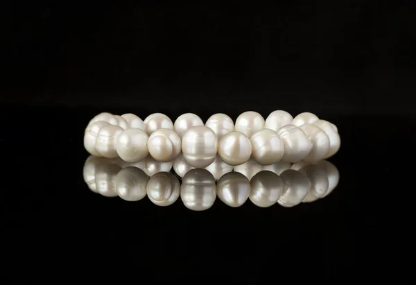 Pearl bracelet on a black mirror surface — Stock Photo, Image