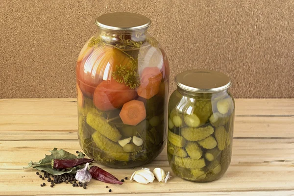 En glasburkar med saltade gurkor och tomater och några kryddor — Stockfoto