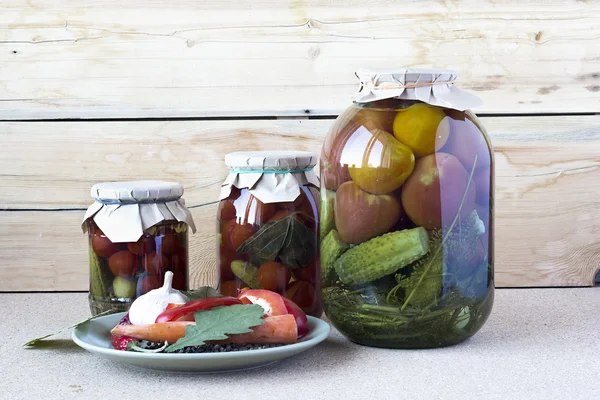 Salted tomatoes and cucumbers in a glass banks with spices on a — Stock Photo, Image