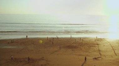 Sunset 'te plajda futbol oynayan genç erkekler Atlantik Okyanusu' nun ağır çekim sahili üzerinde siluet, Fas 'ın Taghazout sahili, 4k