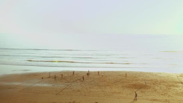 Jonge mannen die voetballen op het strand bij zonsondergang, Silhouet van mensen op het strand van de Atlantische Oceaan slow motion, Taghazout kustlijn, Marokko, 4k — Stockvideo