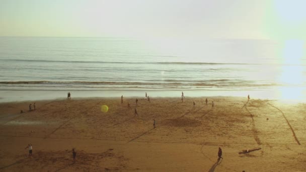 Fiatal férfiak fociznak a strandon naplementekor, Silhouette of people on the beach of Atlantic ocean slow motion, Taghazout tengerpart, Marokkó, 4k — Stock videók