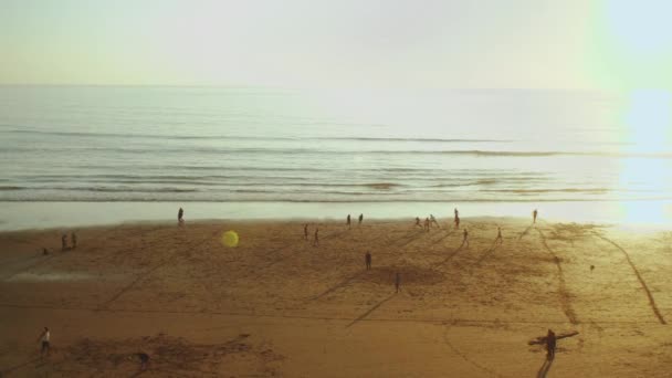 Ludzie grający w piłkę nożną na plaży o zachodzie słońca, Sylwetka ludzi na plaży Oceanu Atlantyckiego slow motion, Maroko, 4k — Wideo stockowe