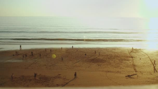 Sylwetka ludzi na plaży Oceanu Atlantyckiego w zwolnionym tempie, osoby grające w piłkę nożną na plaży o zachodzie słońca, wybrzeże Taghazout, Maroko, 4k — Wideo stockowe