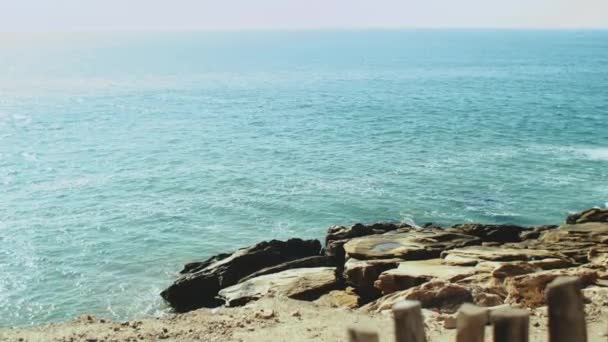 Ralenti, l'eau de l'océan Atlantique lors d'une marée qui s'écrase sur un rivage pierreux, les vagues frappent les pierres légèrement, temps ensoleillé et ciel clair, Maroc 4k — Video