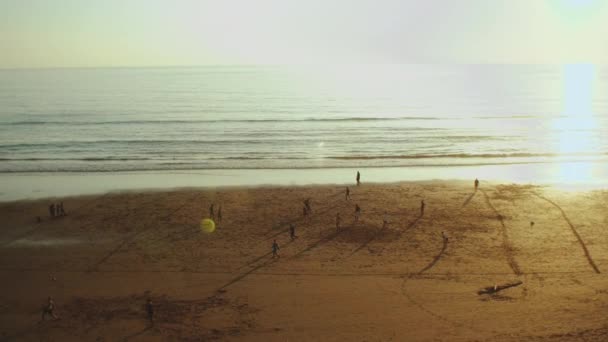 Persone che giocano a calcio sulla spiaggia al tramonto, Silhouette di persone sulla spiaggia dell'oceano Atlantico slow motion, Marocco, 4k — Video Stock