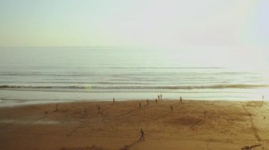 Atlantik Okyanusu 'nun kumsalında ağır çekimde insanların silueti Sunset, Fas' ta futbol oynayan insanların silueti.