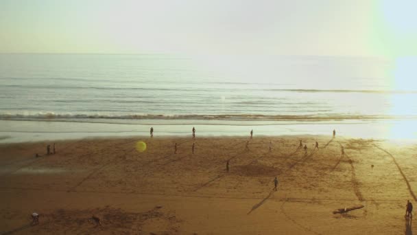 Sylwetka ludzi na plaży Oceanu Atlantyckiego zwolniony ruch, ludzie grający w piłkę nożną na plaży o zachodzie słońca, Maroko, 4k — Wideo stockowe