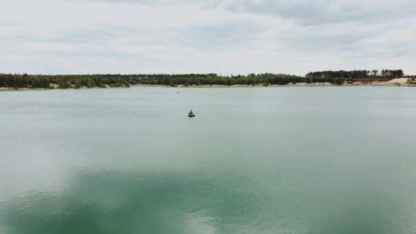 Pria kesepian di perahu di tengah danau, danau pemandangan alam musim panas dengan hutan pohon pinus. Alam Ukraina, udara di atas danau yang indah dan hutan hijau — Stok Video