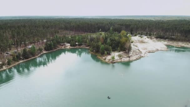 Letecký pohled na zelený les a břeh jezera. Osamělá loď uprostřed jezera, jezero letní přírodní krajina s borovicovým lesem. Příroda Ukrajiny, Vzduch nad krásným jezerem a zeleným lesem — Stock video