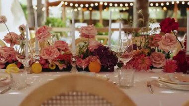 Çiçeklerle, mumlarla, taze parlak çiçeklerle süslenmiş düğün masası. Çiçek aksanlı romantik bir açık hava düğünü zarif masalı güzel bir bohem mekanı. Yüksek kalite 4k görüntü