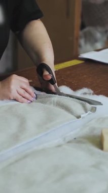 Dikey video. Mobilya fabrikasında kanepe üretimi için kadın eli sünger kauçuk kumaş makasıyla yakın çekim. Döşeme mobilyası üretimi. Yüksek kalite 4k görüntü