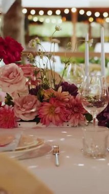 Romantik açık hava masa dekoru, mumlarla süslenmiş zarif çiçek süsü, yemyeşil çiçeklerle süslenmiş büyüleyici açık hava düğün ortamı.